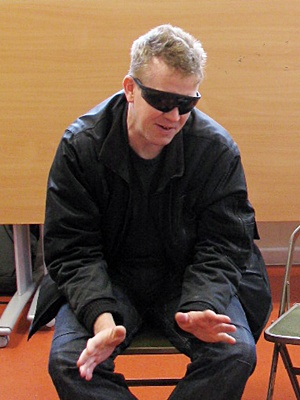 Man indoors sitting with sunglasses on