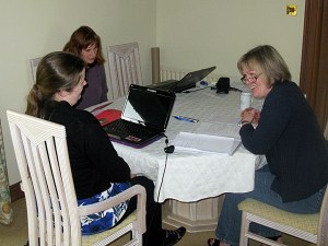 Three women sitting around a table with laptops and meeting papers