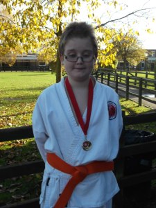 Elliot wearing a white gi with red belt and a gold medal around his neck