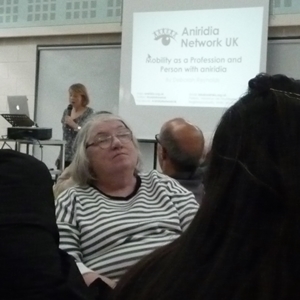 Woman listening with a presenter and screen in the background