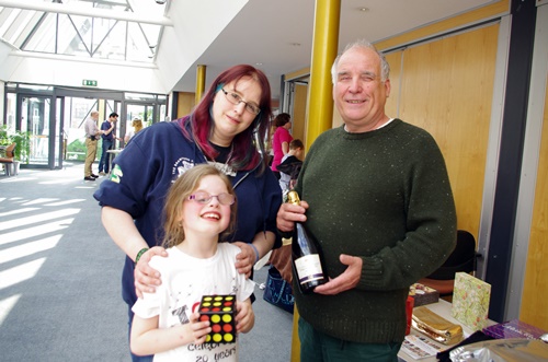 Mum and daughter with a cube toy alongside a man with a bottle of wine