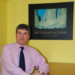 Fintan standing beside a poster on which the main word is determination