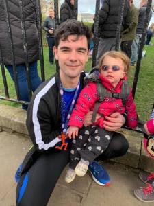 Edward wearing his half marathon medal and holding Sabrina, who has aniridia.