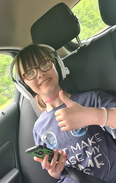 Child wearing glasss and headphones in the rear seat of car