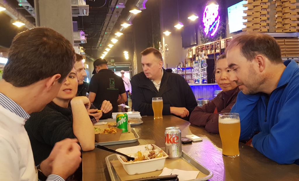 4 men and two women talking around a table with food and drinks