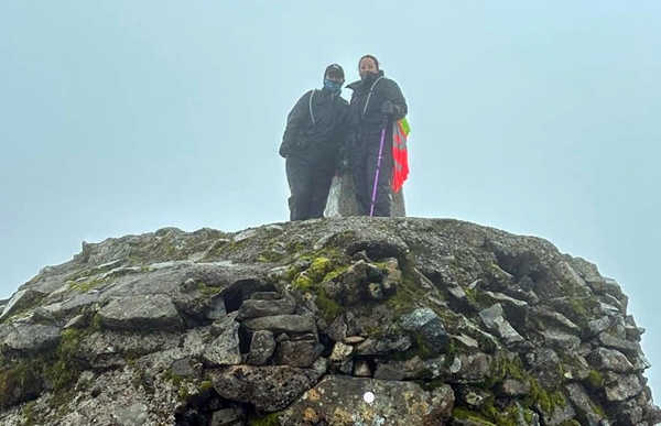 Gemma and another person standing atop the final summit of a mountain