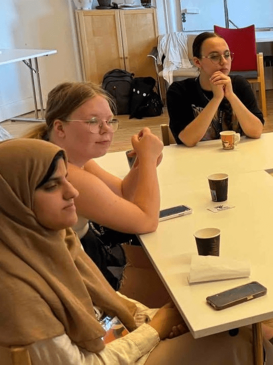 3 young women with aniridia sitting at desk listen to a presenter