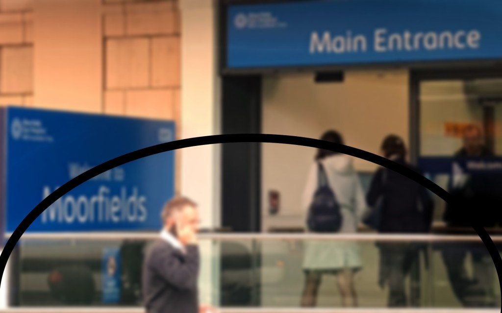 Blurry image of Moorfields entrance, simulating the view with a reduced bubble. The black line is now a semi-circle anchored on the bottom corners of the image. Text can be discerned and potentially read if large or backlit. Major features of people such as hair and clothes can be distinguished