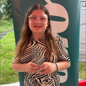 Young girl in zebra stripe blouse holding a transparent engraved award